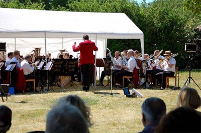 Andreas Wetterlund dirigerar dagens Limhamns Brassband i Soldattorpets trädgård.
